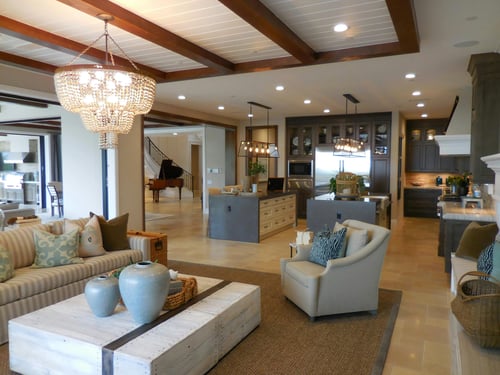 A luxury coastal kitchen and living area with large windows natural light white oak tones and indoor-outdoor connection.